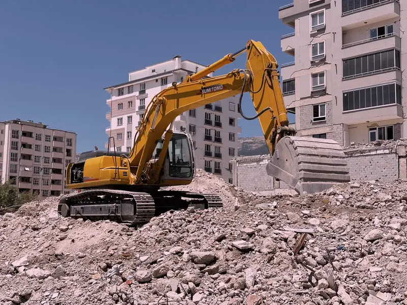 حفارة تزيل أنقاض الهدم في موقع بناء